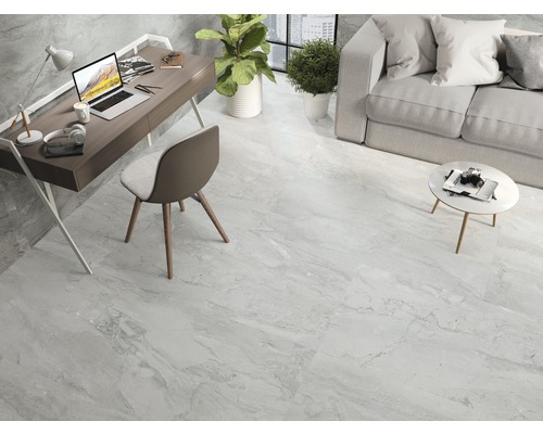 Heller Wohnraum mit Fliesenboden in Marmoroptik, Schreibtisch, Sofa und Pflanzen.
