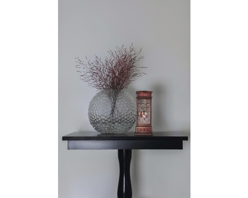 Dekorative Szene mit einer Vase, Pflanzen und einer Laterne auf einem Tisch