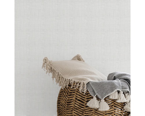Dekokissen und Decke in einem Weidenkorb vor einer Wand