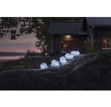 Dekorative Lichterkette mit Igel-Motiv auf einem Stein im Garten.