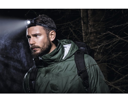 Mann mit Varta Stirnlampe und Rucksack im Freien