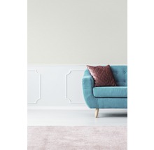 Teilansicht eines Wohnzimmers mit türkisfarbenem Sofa, Kissen und Teppich
