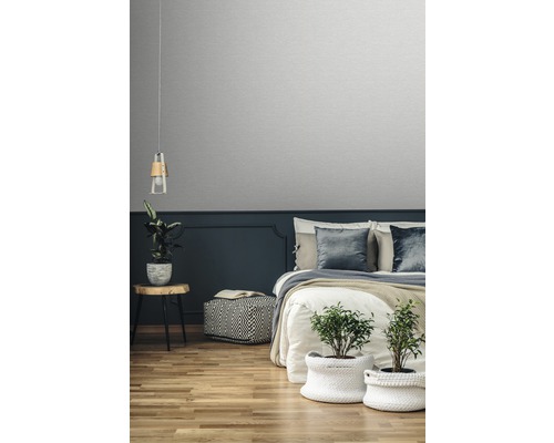 Schlafzimmer mit Bett, Nachttisch, Lampe, Pflanzen und Tapete