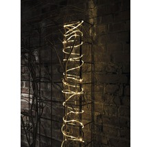 Dekorative Lichterkette auf einem Metallgitter mit Ästen vor einer Ziegelwand