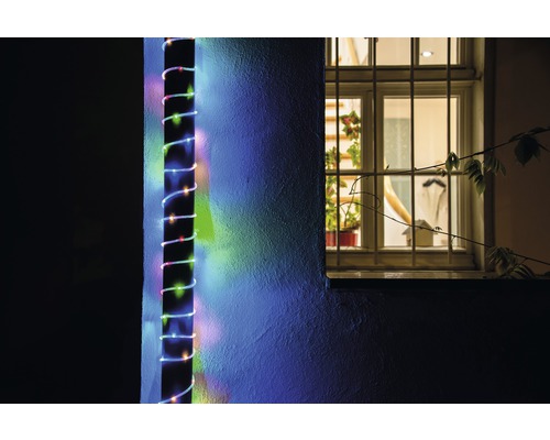 Außenaufnahme einer Hauswand mit einer daran befestigten LED-Lichterkette neben einem Fenster.