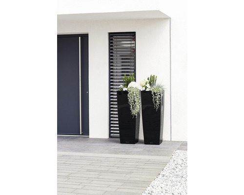 Zwei hohe, bepflanzte Pflanzgefäße aus Kunststoff vor einem Gebäude.