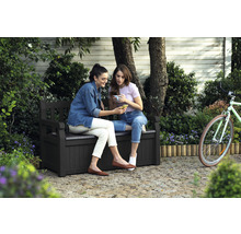 Zwei Frauen sitzen auf einer Gartenbank mit Stauraum und schauen auf ein Smartphone.