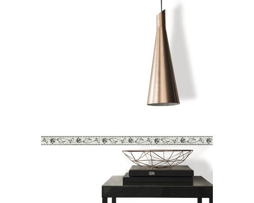 Dekorative Bordüre mit Blumenmuster an einer weißen Wand, kombiniert mit einer Hängelampe und einem Beistelltisch.