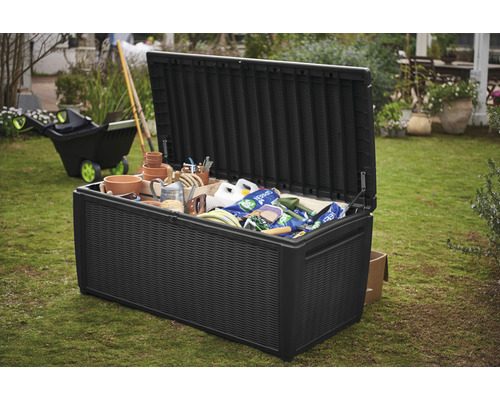 Geöffneter, schwarzer Gartentruhe gefüllt mit Gartenzubehör im Garten