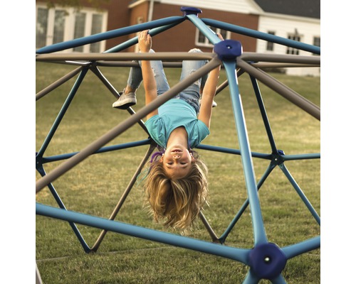 Mädchen hängt auf einem Klettergerüst im Garten