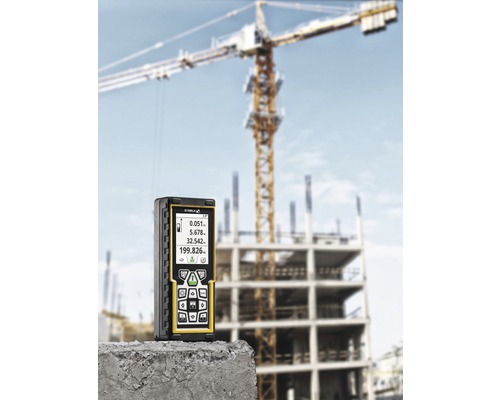 Laser-Distanzmessgerät vor einer Baustelle mit Kran im Hintergrund