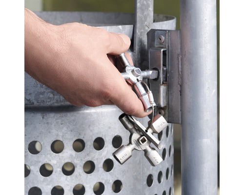 Ein Mann öffnet mit einem Universalschlüssel ein Schloss an einem Abfallbehälter.