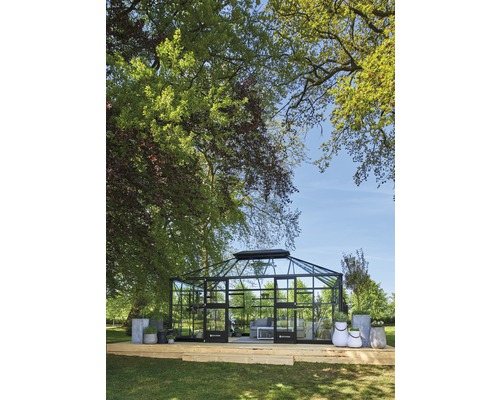 Gewächshaus mit Glasfront und Sitzgelegenheit im Garten.