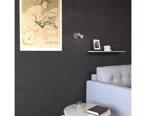 Wohnzimmer mit Kunstposter, Wandleuchte, Regal und Sofa