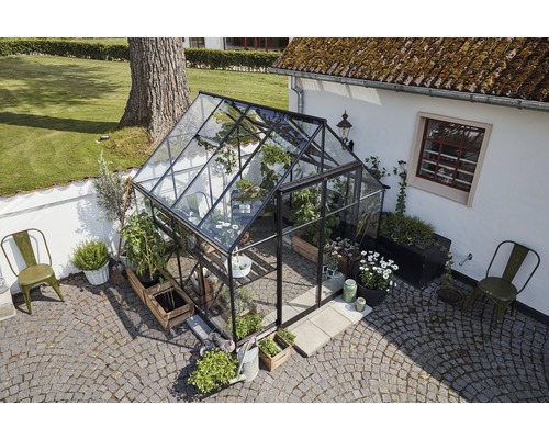 Gewächshaus mit Pflanzen und Gartenmöbeln im Außenbereich