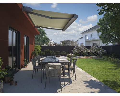 Terrasse mit Markise, Tisch und Stühlen in einem Garten.