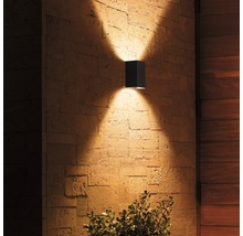 Quadratische Außenwandleuchte aus Metall mit Lichteffekten an einer Steinwand