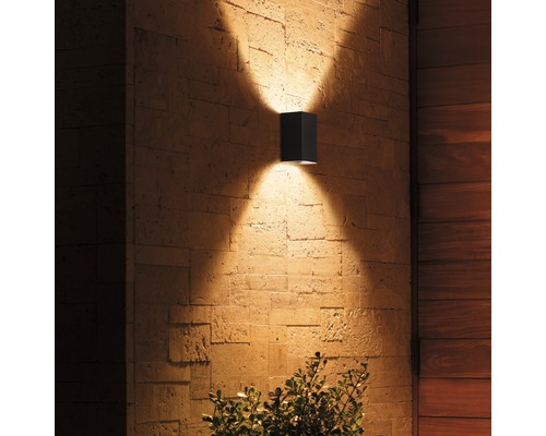 Quadratische Außenwandleuchte aus Metall mit Lichteffekten an einer Steinwand