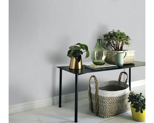 Raumansicht mit Tisch, Pflanzen und Dekoration vor einer einfarbigen Wand