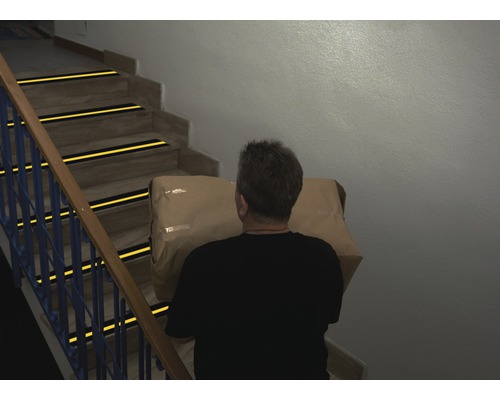 Mann trägt Paket auf Treppe mit Antirutschstreifen