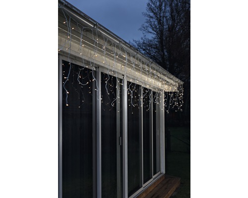 Beleuchtete Eiszapfenlichterkette am Dach eines Hauses