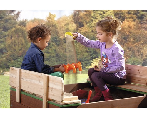 Zwei Kinder spielen in einem Sandkasten mit Sandspielzeug.