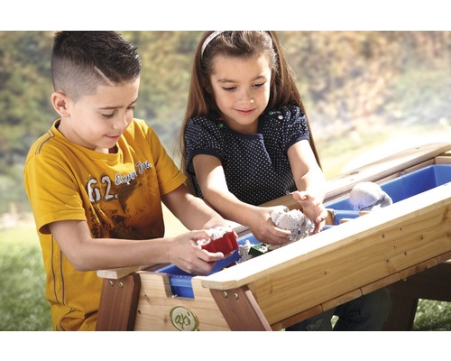 Zwei Kinder spielen mit einer Sandkiste im Freien.