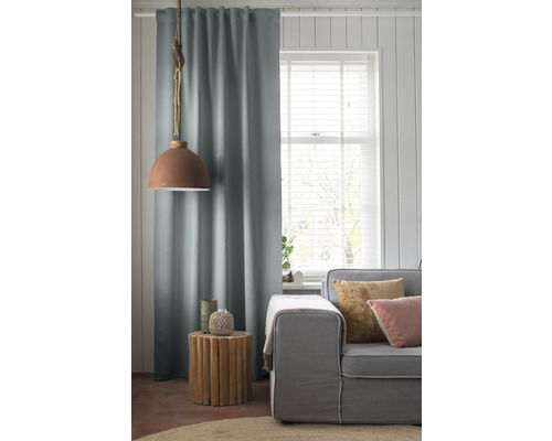 Wohnzimmer mit Vorhang, Lampe, Beistelltisch und Sofa.