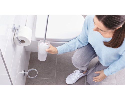 Frau reinigt Toilette mit einer Toilettenbürste im Badezimmer.