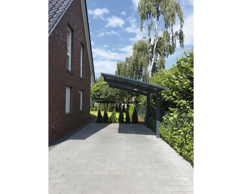 Einfahrt mit Pflastersteinen und Carport neben einem Backsteinhaus
