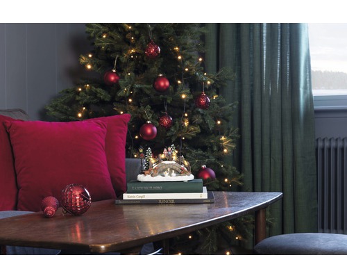 Weihnachtsdekoration mit Baum, Kugeln, Lichterkette und dekorativer Winterlandschaft auf einem Tisch