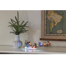 Dekorative Szene mit Tannenzweigen in einer Vase, einer beleuchteten Weihnachtsmannschlittenfigur und einer Karte von Südamerika.