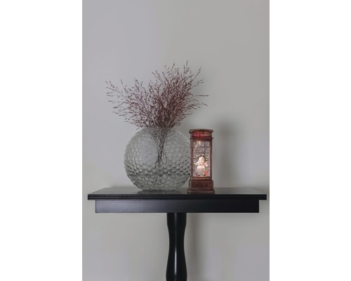 Dekorative Blumenvase mit Trockenblumen und Schneekugel auf einem Tisch