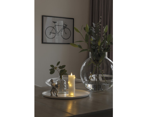Dekoratives Arrangement mit Vase, Kerze und Figur auf einem Tisch mit Fahrradbild im Hintergrund.