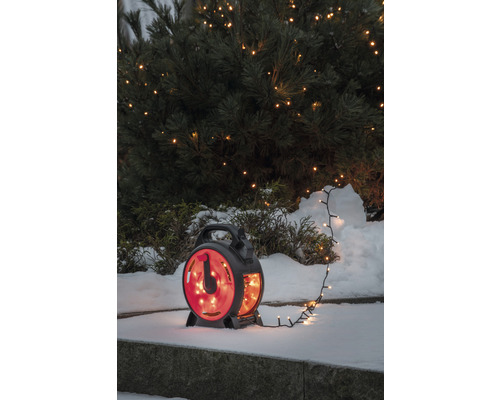 Lichterkette auf Kabeltrommel vor schneebedecktem Busch