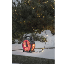 Lichterkette auf Kabeltrommel im Schnee vor beleuchtetem Baum