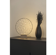 Dekorative Tischleuchte mit abstrakten Lichtpunkten neben einer Vase auf einem Schrank