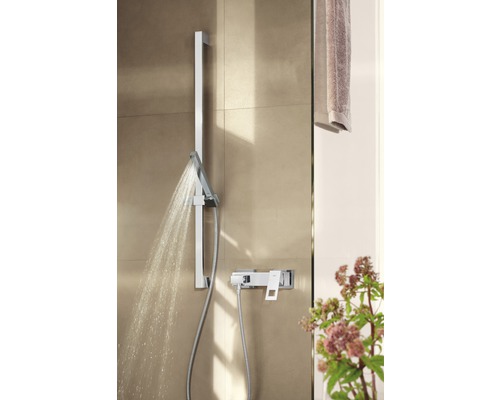 Duscharmatur mit Brausekopf und Wasserstrahl im Badezimmer.
