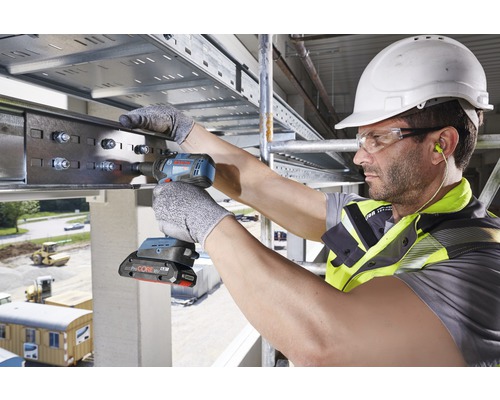 Ein Arbeiter befestigt eine Metallschiene mit einem Akku-Schlagschrauber an einer Decke
