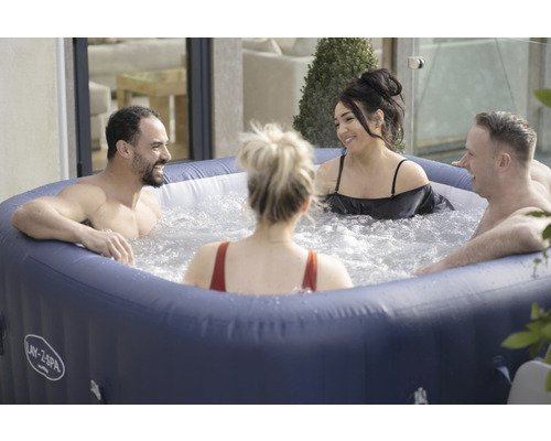 Gruppe von Personen in einem aufblasbaren Whirlpool der Marke Lay-Z-Spa im Aussenbereich.