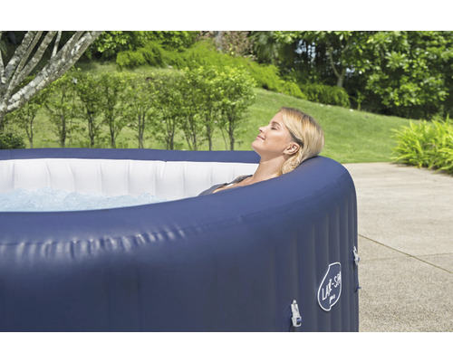 Frau entspannt im aufblasbaren Whirlpool im Garten.