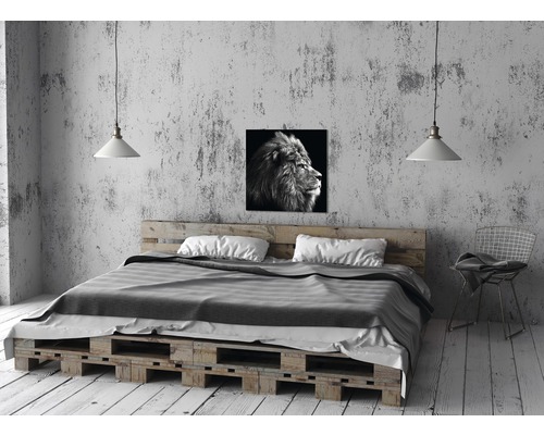 Schlafzimmer mit Bett aus Paletten, Lampe und Löwenbild