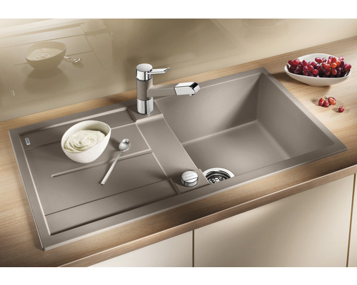 Spüle mit Abtropffläche, Küchenarmatur und Speisen auf einer Küchentheke.