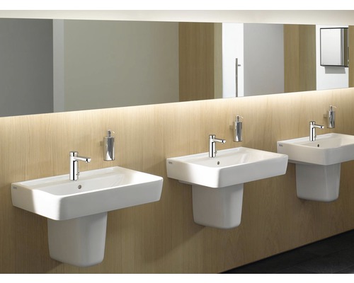 Drei weiße Waschbecken mit Armaturen und Seifenspendern in einem Badezimmer.