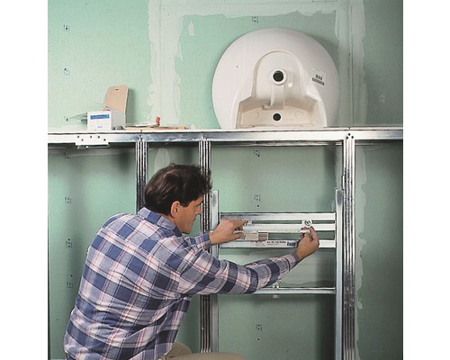 Ein Mann montiert ein Vorwandelement für ein Waschbecken im Badezimmer.