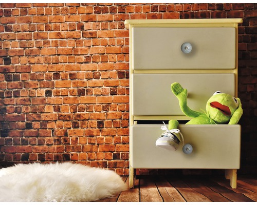 Kommode mit drei Schubladen, einer Stoffpuppe und einem Schuh vor einer Ziegelwand