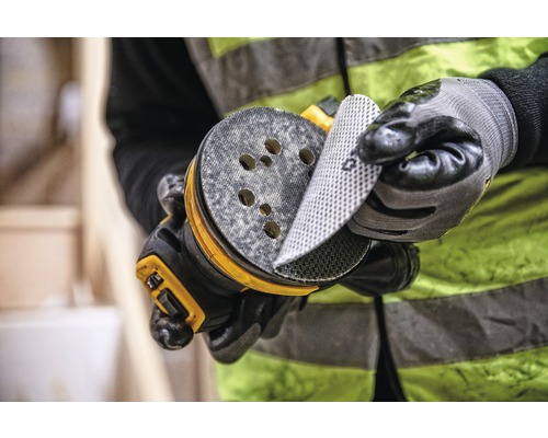 Ein Mann wechselt Schleifpapier auf einem Exzenterschleifer.