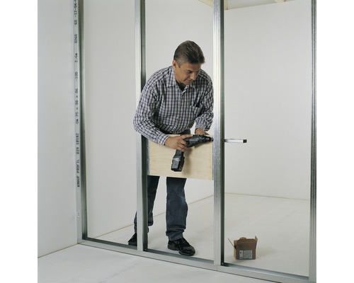 Mann montiert mit einem Akkuschrauber eine Trockenbauwand.