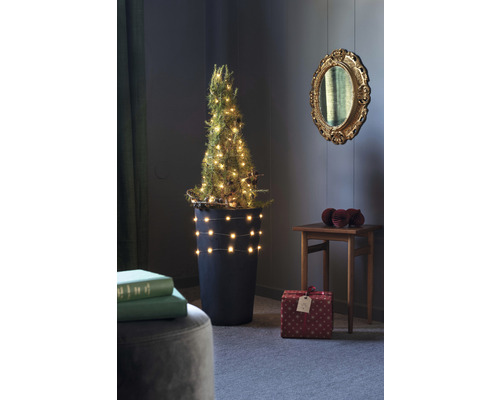Dekorierter Miniaturweihnachtsbaum in einem Topf mit Geschenken in einem Raum