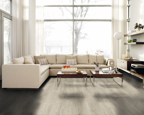 Heller Wohnraum mit Ecksofa, Couchtischen und Laminatboden